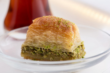 Baklava with pistachio and turkish cup of tea on a white background