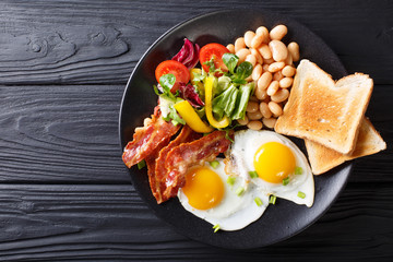 Delicious fried eggs, bacon, beans, toast and fresh vegetable salad on a plate. horizontal top view