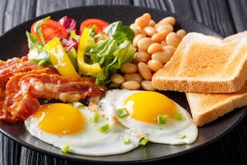Delicious fried eggs, bacon, beans, toast and fresh vegetable salad on a plate. horizontal