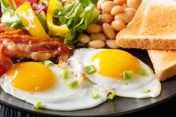English breakfast macro: fried eggs, bacon, beans, toast and fresh vegetable salad. horizontal