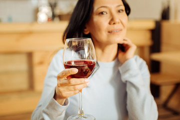 Thinking. Attractive thoughtful dark-eyed woman thinking and looking in the distance while drinking red wine