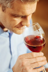 Wine. Attractive serious blond man drinking wine and wearing a blue shirt while relaxing
