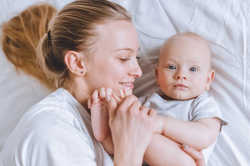 top view of mother cuddling with her infant baby in bed