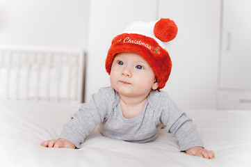 portrait of cute little infant child in santa hat lying on bed