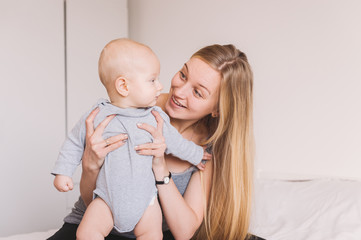 beautiful young mother hugging and lookign at adorable infant child