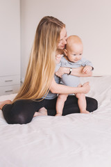 Fototapeta na wymiar beautiful young mother hugging adorable little child while sitting on bed