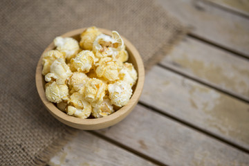 Popcorn in round wooden bowl on wooden table background, movie time snack