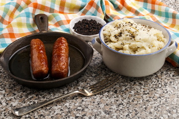 peppered mashed potato in a bowl and sausages