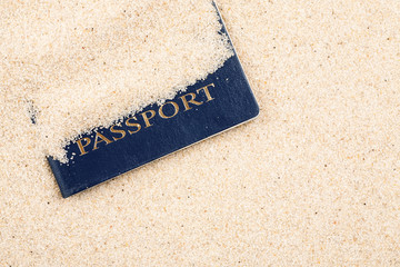 Blue passport covered with sand on a beach, top view