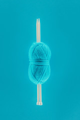 blue knitting yarn ball with knitting needles, isolated on blue