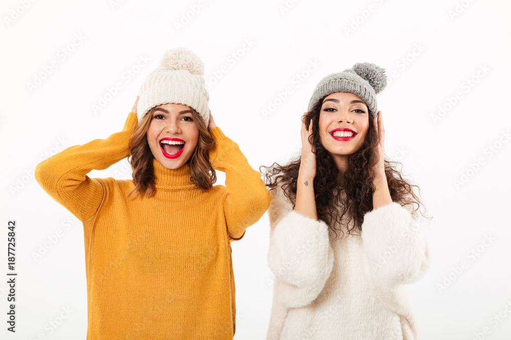 Sticker Two funny girls in sweaters and hats having fun together