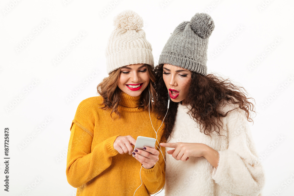 Sticker two beauty girls in sweaters and hats standing together