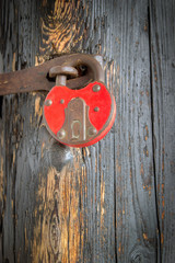 Old rusted padlock on wood background.