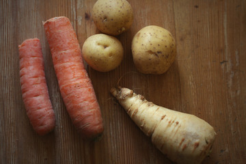 Carrots,potato and parsnip at a wooden table