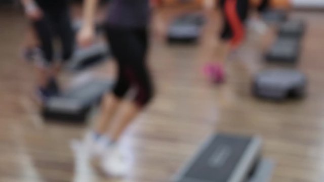 Young healthy sportive women training at gym using step boards. Out of focus video footage.