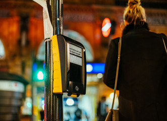 Woman silhouette and push button and wait for siganl opposite sign on the rossing ligt street...