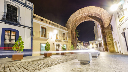 Trajano Arch at night with car light trail in Merida