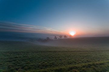 Misty winter morning sunrise over the hill on the South Downs near Hambledon, Hampshire, UK