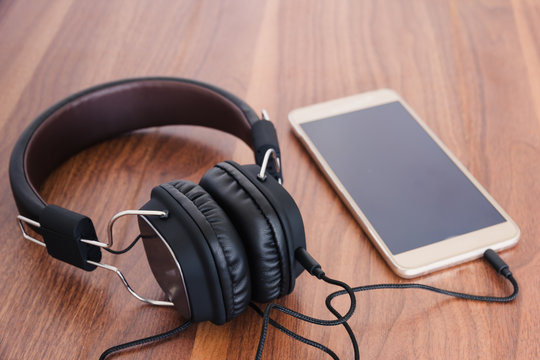 Smartphone and headphone on wooden background for listen to music