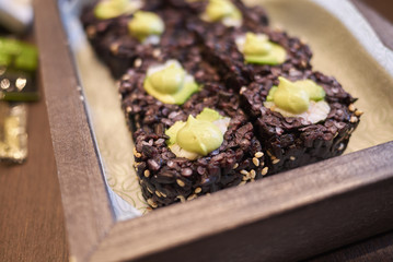 Milan, Italy - December 17, 2017 : Black rice rolls with avocado and shrimps