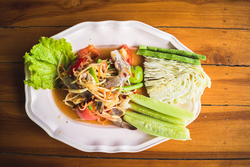 a plate of food with a variety of ingredients including shredded vegetables, shrimp, and a red sauce.