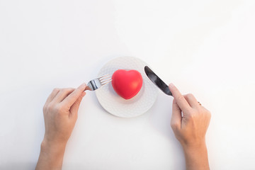 composition on a white background of the plates, heart-shaped, hands with fork and knife