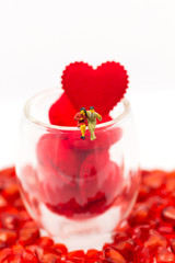 The couple sit at the edge of a glass with a glass full of hearts. Using as valentine day concept.