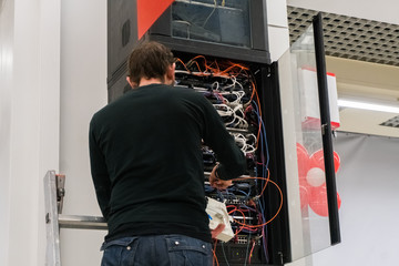 Young engeneer man in network server room connecting wires