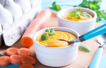 Spoon and casserole with tasty carrot souffle on wooden table