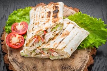 Tortilla wraps with grilled chicken or vegetarian tarteel of fresh vegetables on a wooden background.