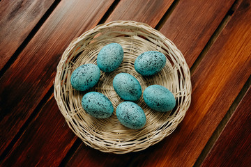Easter eggs blue speckled on wicker basket on rustic wooden background