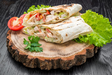 Tortilla wraps with grilled chicken or vegetarian tarteel of fresh vegetables on a wooden background.
