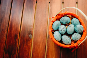 Blue speckled easter eggs in a wicker red lined basket on dark wooden background  aligned right