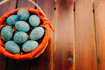 Blue speckled easter eggs in a wicker red lined basket on dark wooden background close up aligned left