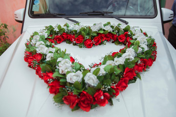 White, red heart bouquet on white bridal car. Wedding car and petals on top. Luxury wedding car...