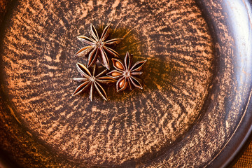 Stars of dried anise (Illicium verum) on natural background, close up. Christmas aromatic spices on a rustic old brown plate. 