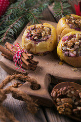 Fototapeta na wymiar Baked apples stuffed with berries, walnuts and honey on a wooden cutting board.