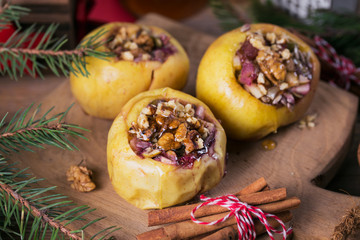 Baked apples stuffed with berries, walnuts and honey on a wooden cutting board.