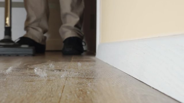 Man cleaning the floor from dust with vacuum cleaner. Close up video.