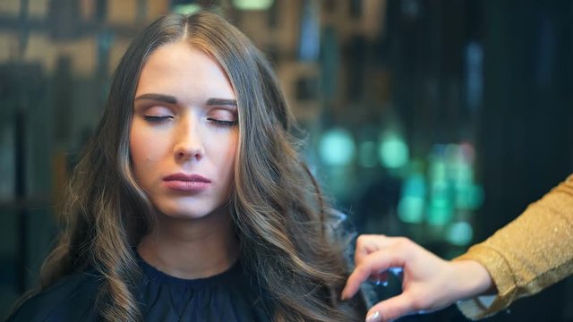 Professional female hairdresser applying spray on client's hair