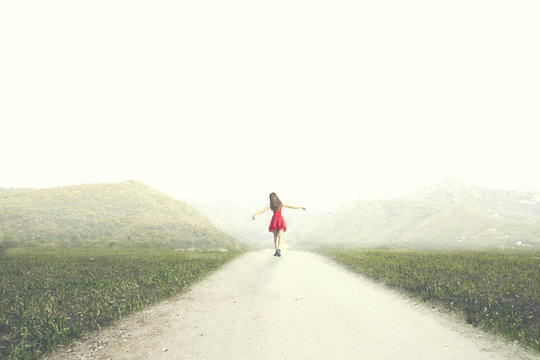 woman with red dress walks happy to infinity in the middle of nature