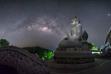 Big Buddha Statue with Milky Way Galaxy in Background at Sumnuk Song Numpu Ron Monastery, Ban Kha, Ratchaburi, Thailand. Long Exposure Night Scape.