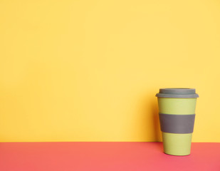 Take out coffee in thermo cup on yellow and pink background.
