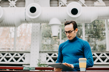 Young and attractive artist, looking for inspiration to write his new book. Using your laptop in a quiet greenhouse while having a coffee. Lifestyle..