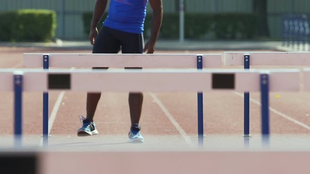Hispanic sportsman stretching and warming up before practicing in hurdle race