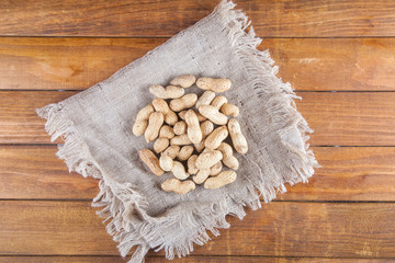 Not peeled peanuts on wooden background