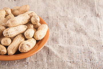 Not peeled peanuts on wooden background