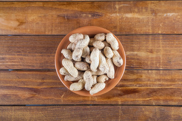 Not peeled peanuts on wooden background. Top view