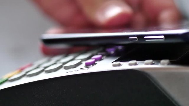 Customer paying with NFC technology by mobile phone on terminal. 4K UltraHD video
