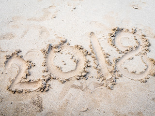 The year of 2018 written in numbers on sand beach. Summer letters.
